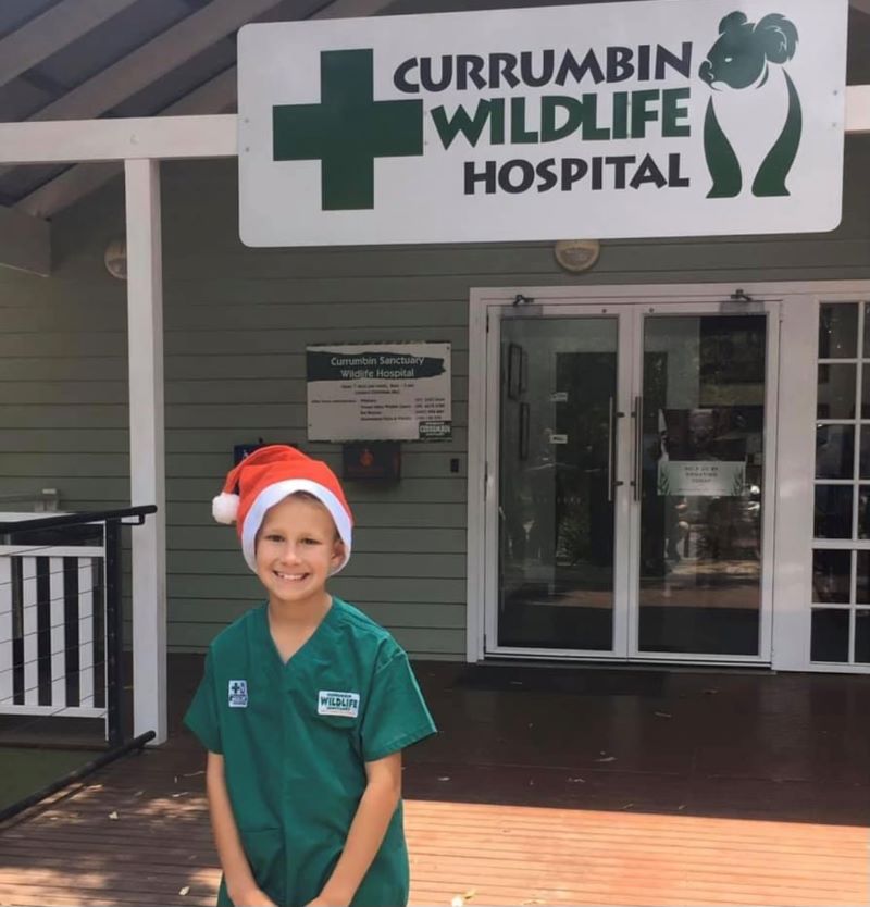 Young Toby Mitchell in front of Currumbin Wildlife Hospital wearing a Christmas hat