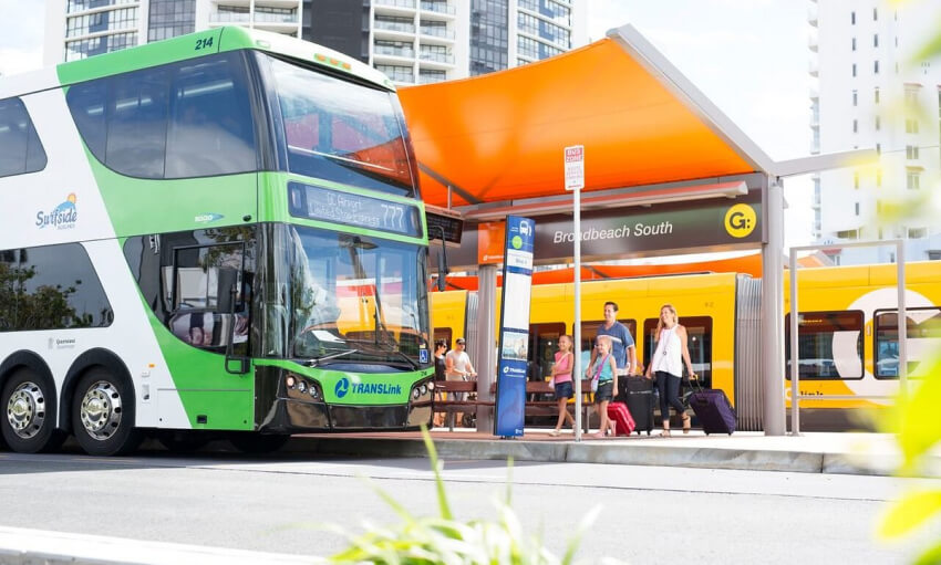 A green and white bus is parked at a bus stop, ready to pick up passengers in a bustling urban environment