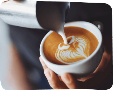 A person gracefully pours steaming coffee from a pot into a white cup, capturing a moment of morning tranquility