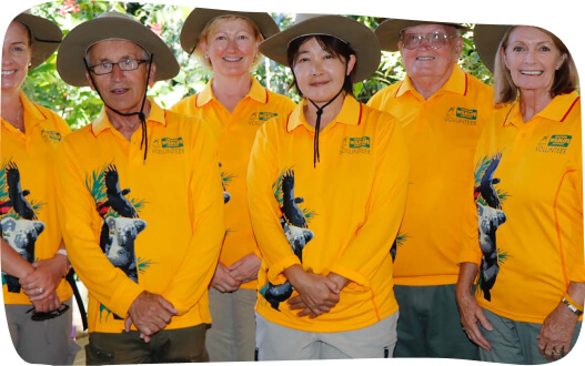 A diverse group of individuals wearing bright yellow shirts and hats, smiling and enjoying their time together outdoors