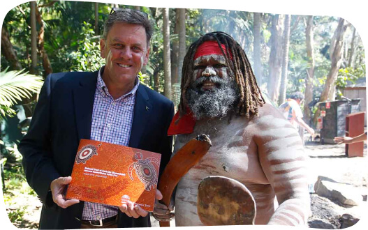 A man proudly holds an award while standing beside another man who is holding a spear