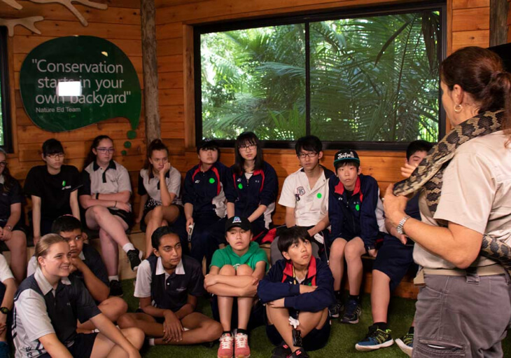 A group of children attentively observing a snake in a classroom setting