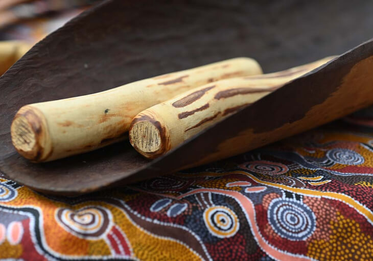 A pair of wooden sticks placed in a handcrafted wooden surface