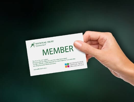 Hand holding a National Trust Queensland member card with text and logo.