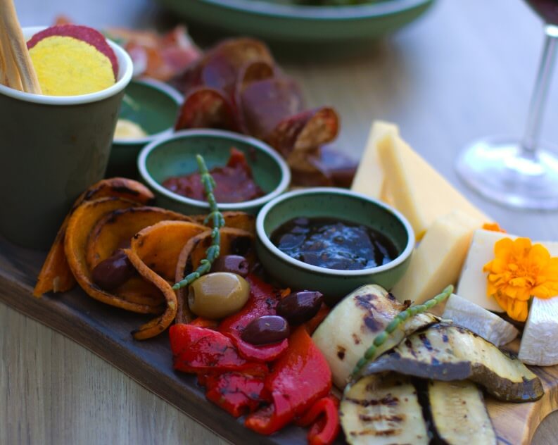 Gourmet charcuterie board featuring grilled vegetables, cheeses, olives, cured meats, and dips.