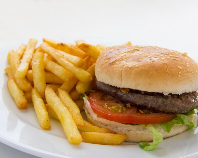 A juicy beef cheeseburger served on a sesame seed bun, filled with fresh lettuce, sliced tomatoes, and a layer of melted cheese.