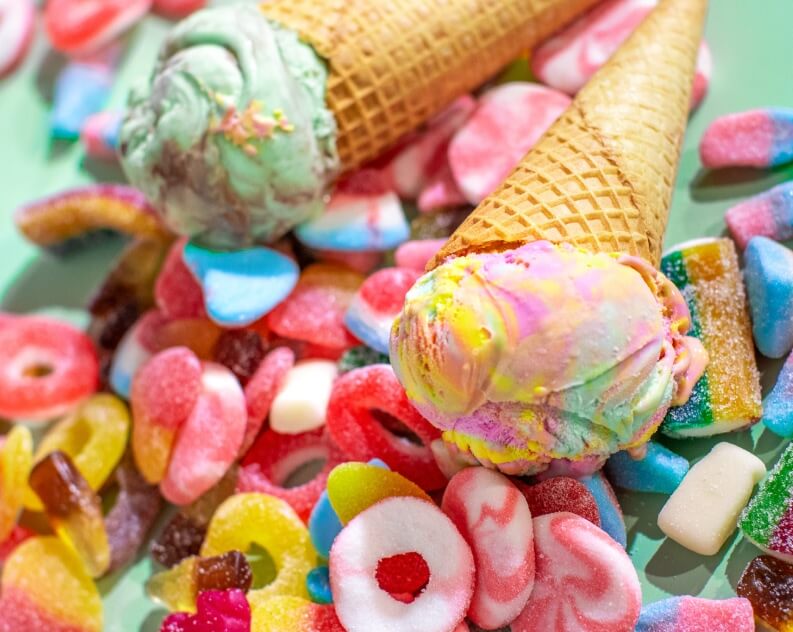 Two waffle cones filled with ice cream, one featuring a vibrant rainbow swirl and the other a mint chocolate chip flavor.