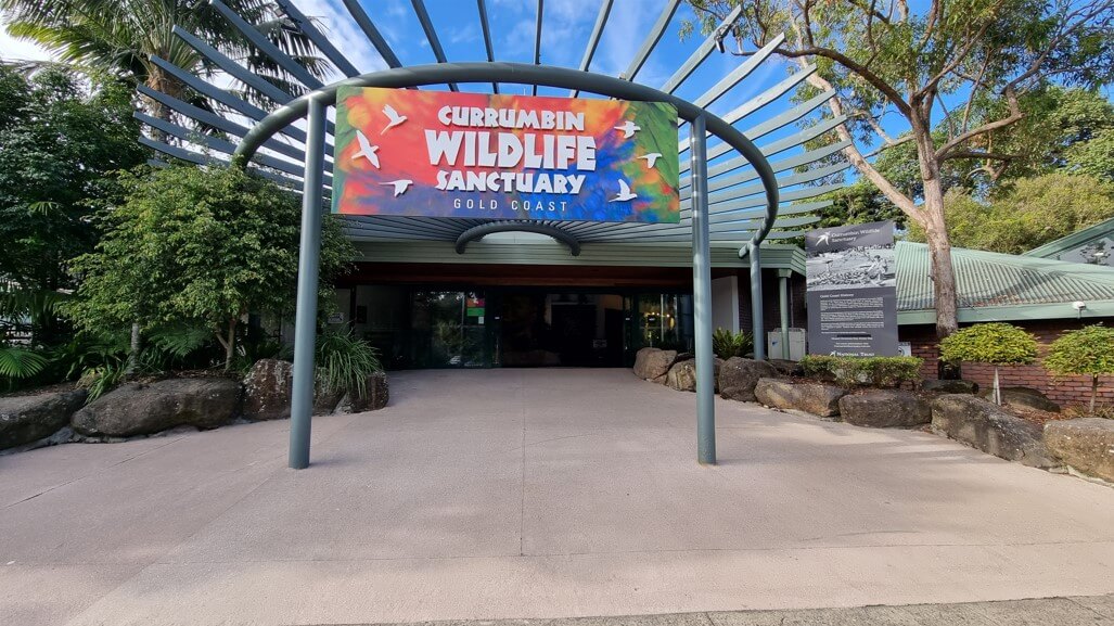Entrance to Currumbin Wildlife Sanctuary on the Gold Coast, featuring a large sign with colorful birds.