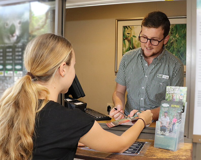 Woman purchasing tour tickets from park ranger at visitor center.