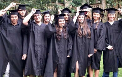 Group of graduating students in black gowns and caps, outdoors.