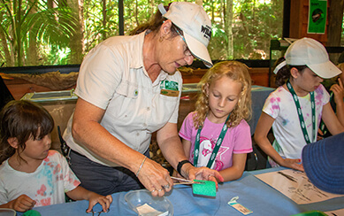 Volunteer helping children craft at a nature center.