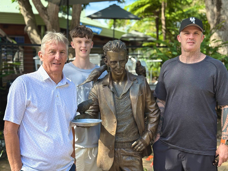 Granddad, dad and son standing next to Alex Griffith statue