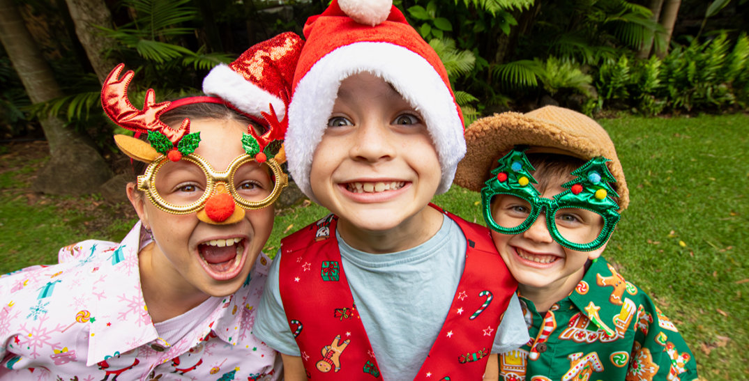 Three young kids taking funny selfie wearing silly Christmas props and outfits