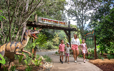 Mum and kids walking on extinction trail, passing a life like dinosaur replica
