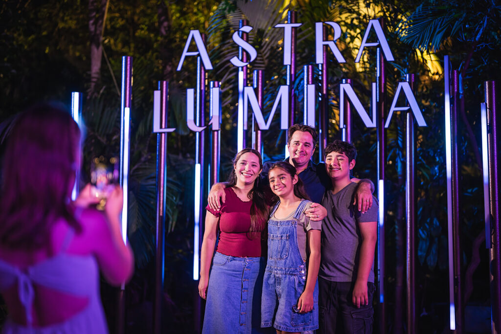 Group posing for a photo at an Astra Lumina event, purple lighting.