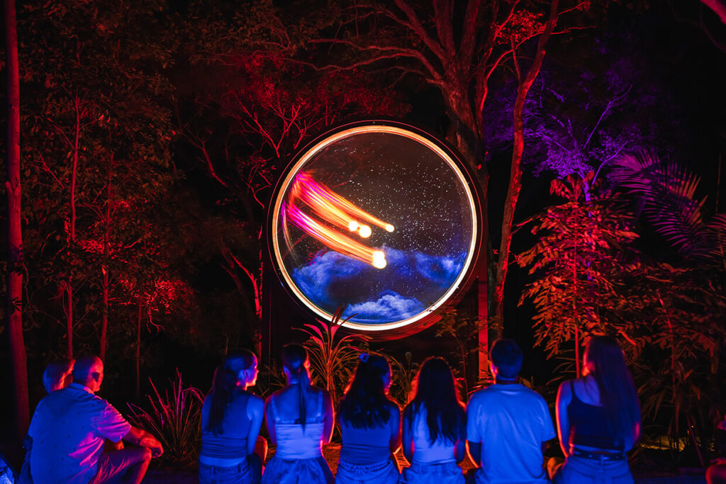 Group watching a glowing cinematic circle display in nature.
