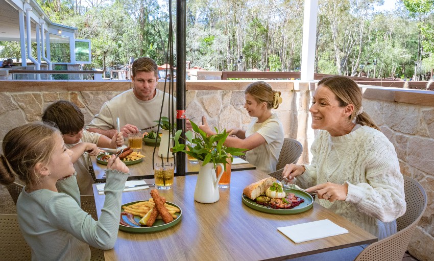 A family of five eating lunch together at a restaurant on an outdoor veranda