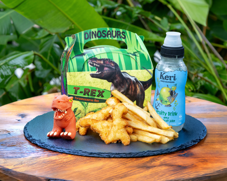 Dinosaur kids meal with dinosaur chicken nuggets and fries, a juice drink and a mini dinosaur finger puppet next to the meal.