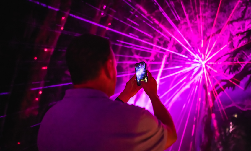 Pink laser light spectacle with a man taking a photo of it