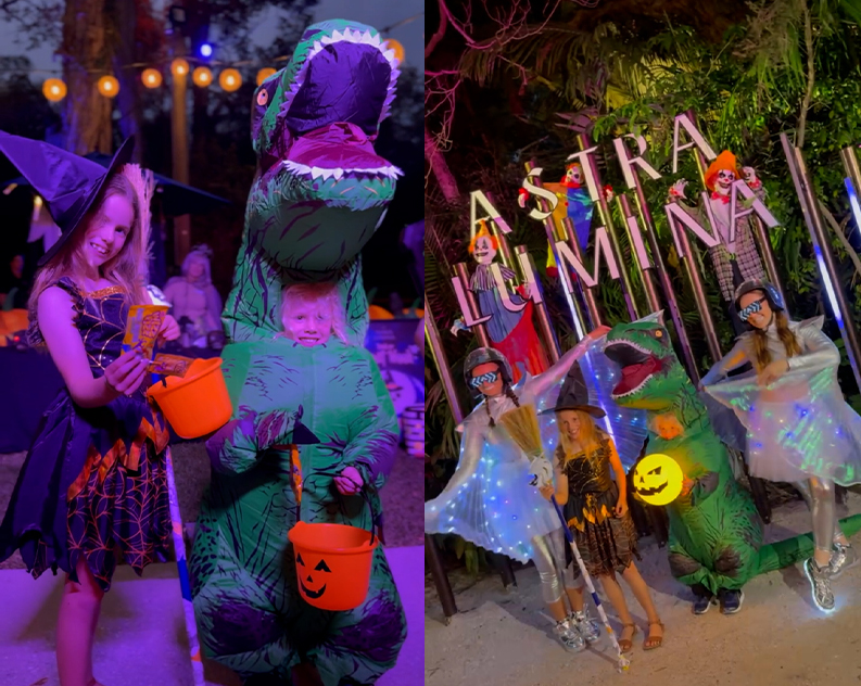 Kids in witch and inflatable T-rex costumes holding pumpkin treat buckets, and posing with light-up winged performers at the Astra Lumina sign